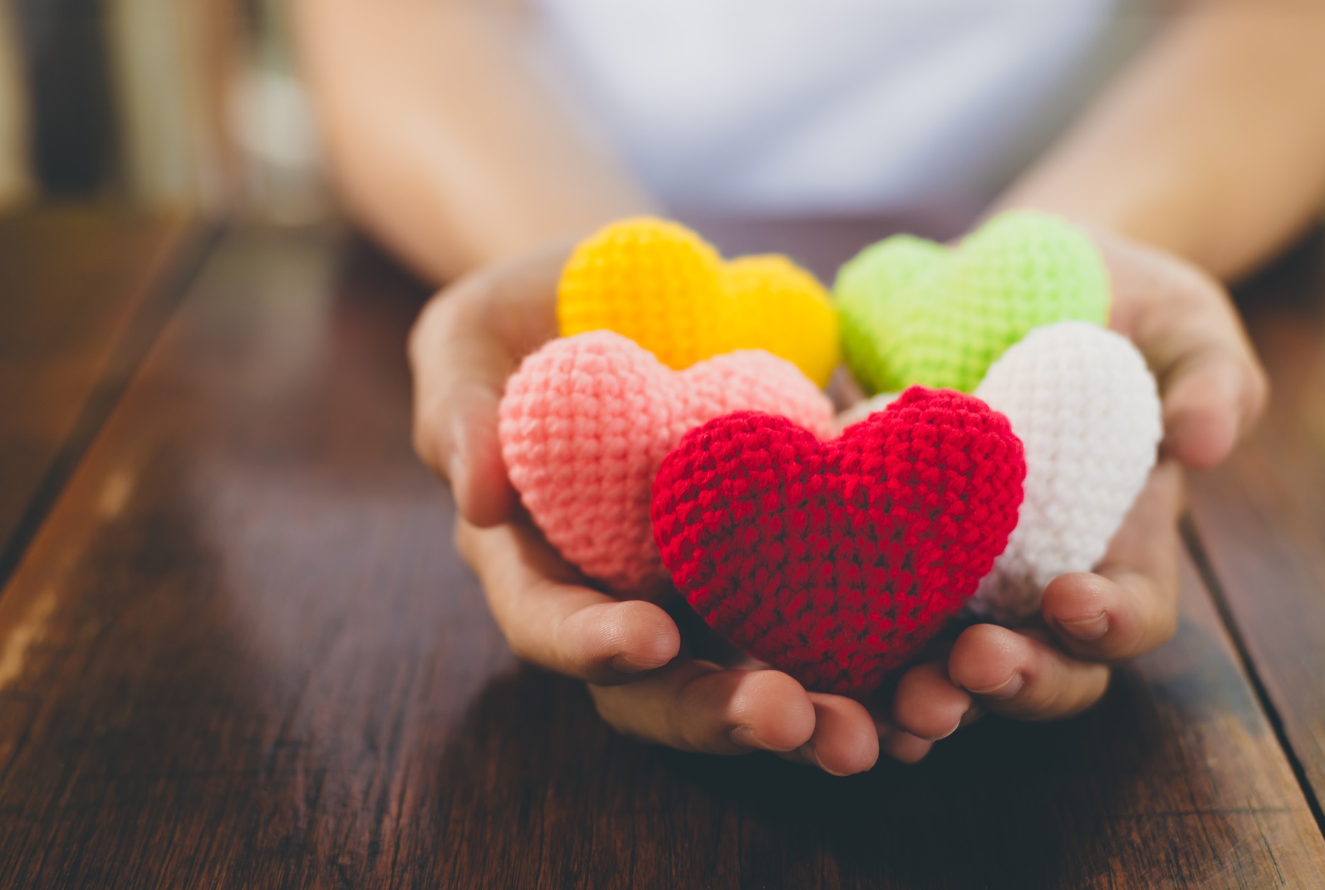 Mixed colors yarn heart on giving hands. Close up of colorful handmade. Healthy heart donation and health care concept. Valentine romance love forever theme